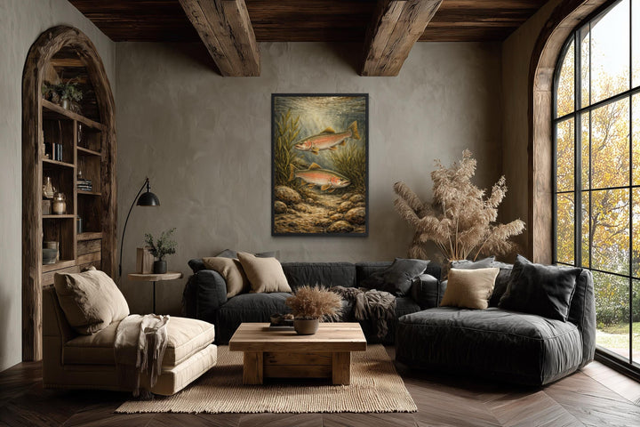 Vertical canvas painting of two trout swimming underwater in a rustic, earth-toned living room.