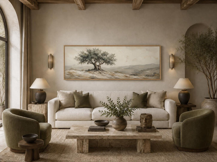 Tuscan olive tree canvas print in sage green and neutral tones above a cream sofa in a living room.