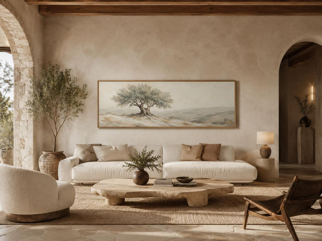 Long horizontal canvas print of a Tuscan olive tree in sage green and taupe above a white sofa.