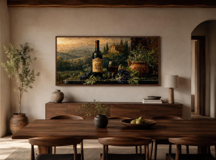 A horizontal canvas painting of a Tuscan wine still life hangs in a modern, minimalist dining room.