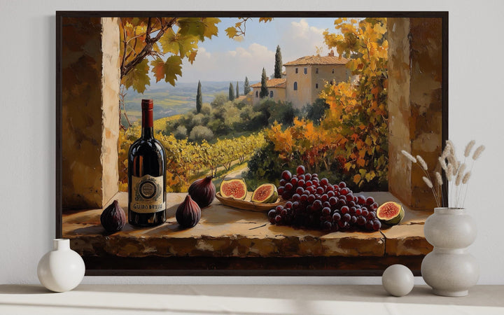 Tuscany vineyard window view wall art with wine bottle, grapes, and figs on a stone ledge.