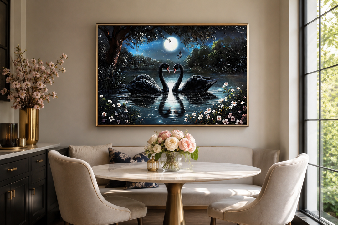Framed canvas art of two black swans on a moonlit lake, hung above a dining table in a modern room.