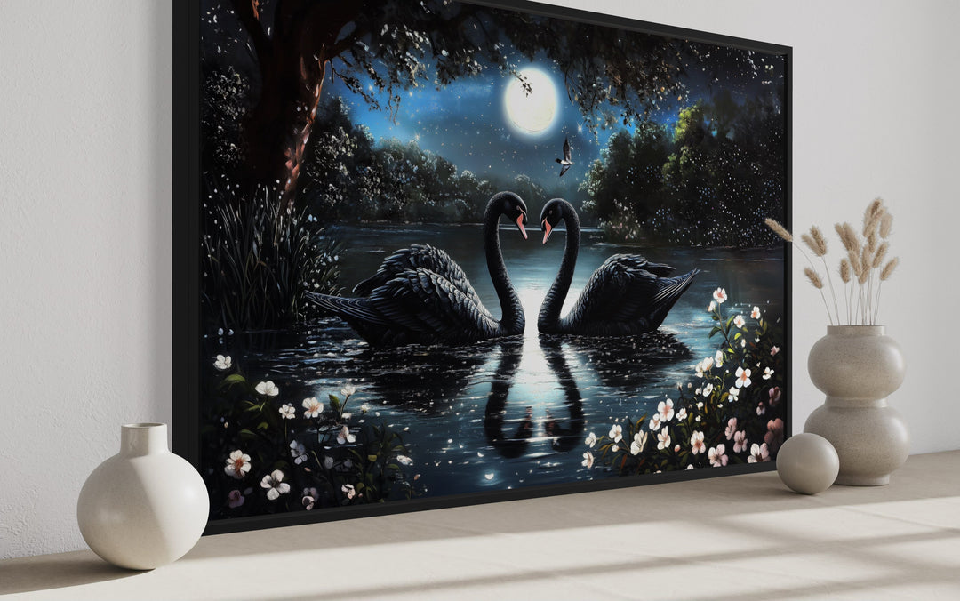 Framed canvas art of two black swans on a moonlit lake with white flowers and a full moon.