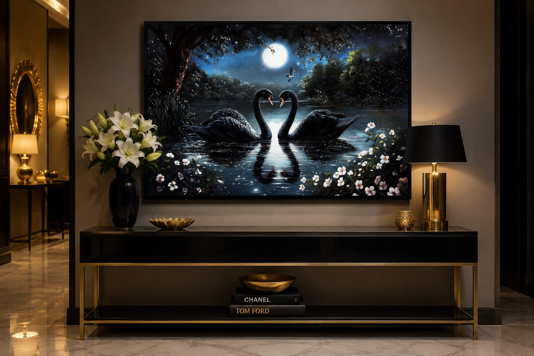 Framed canvas wall art of two black swans on a moonlit lake, displayed above a black console table.