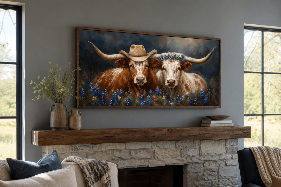 Framed canvas art of two Texas longhorns with a cowboy hat and bluebonnets above a stone fireplace.
