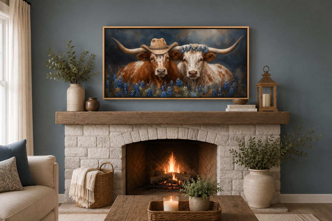 Framed canvas art of two Texas longhorns with cowboy hats and bluebonnets above a brick fireplace.