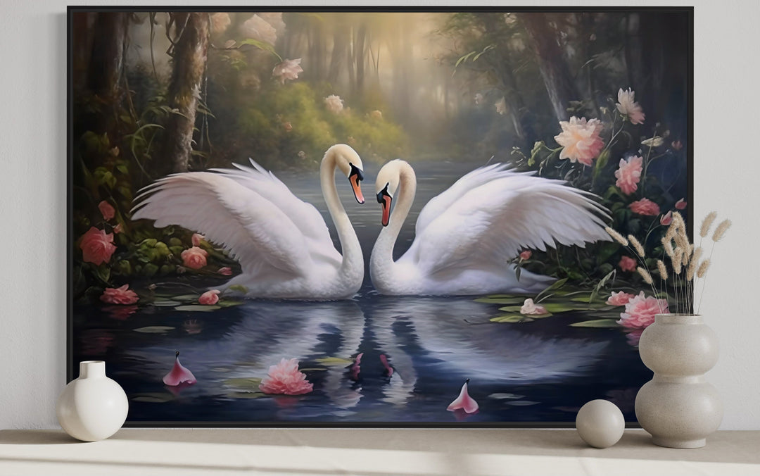 Framed canvas wall art of two white swans on a lake with pink flowers and soft forest light.