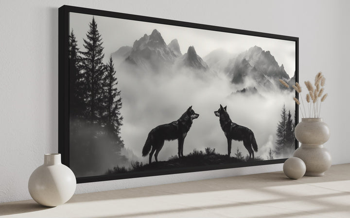Black and white framed canvas art of two wolves on a cliff with foggy mountains for cabin decor.