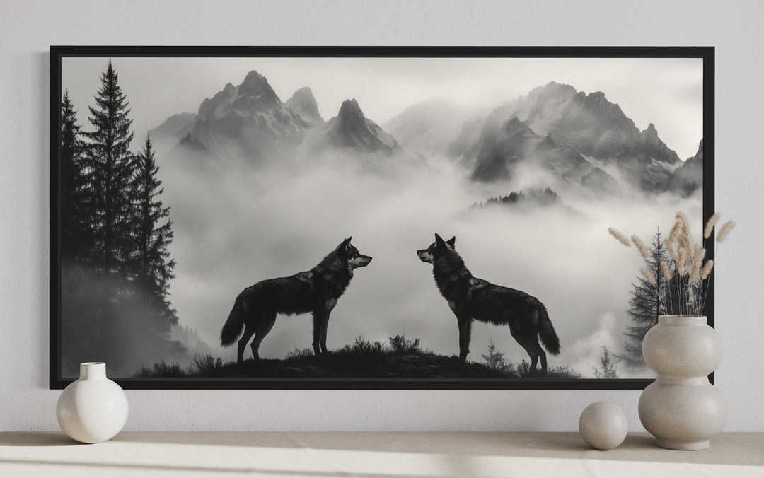 Black and white framed canvas art of two wolves on a cliff in foggy mountains for cabin decor.