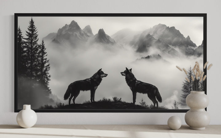 Black and white framed canvas art of two wolves on a cliff in foggy mountains for cabin decor.