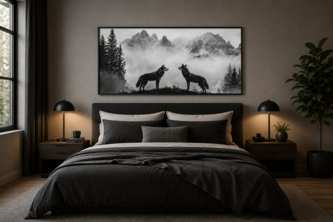 Black and white framed canvas wall art of two wolves on a cliff in foggy mountains above a bed.
