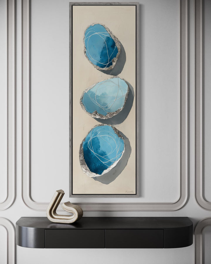 Vertical canvas print featuring three abstract blue and silver stones on a neutral background.