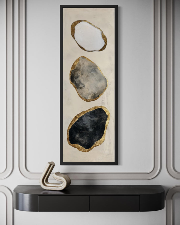 Vertical abstract wall art featuring three stacked rock shapes in white, grey, and black with gold.
