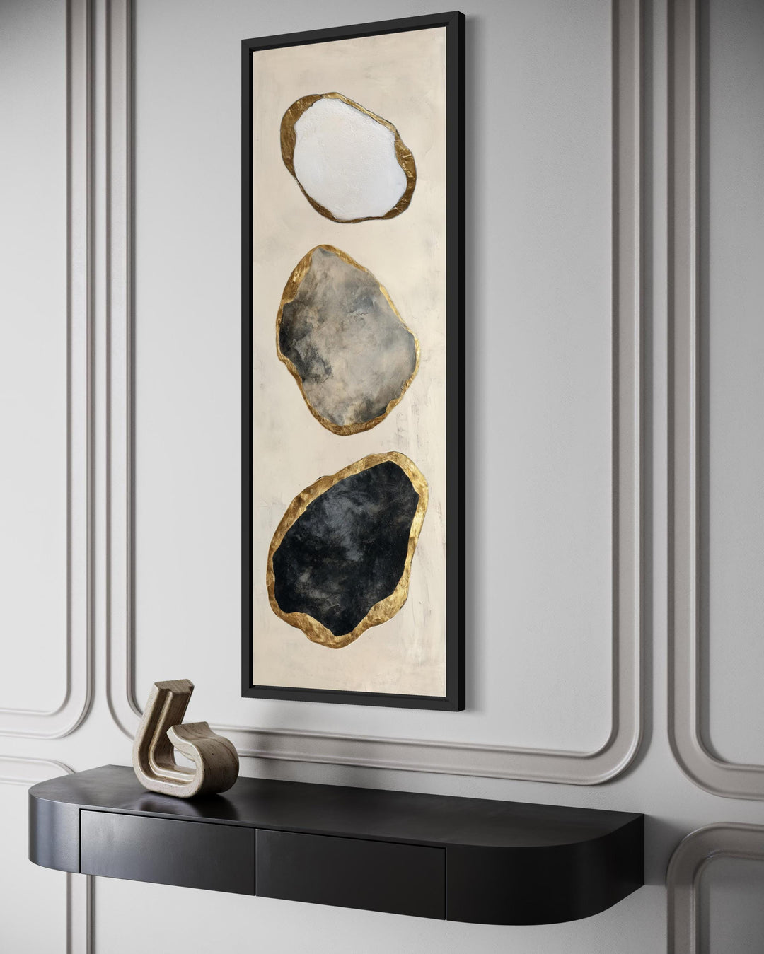 Vertical abstract wall art featuring three stacked rock shapes in white, grey, and black with gold.