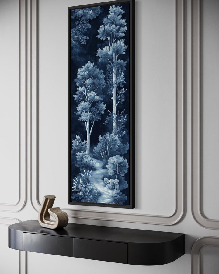 Vertical narrow wall art of a blue and navy night forest scene above a black console table.