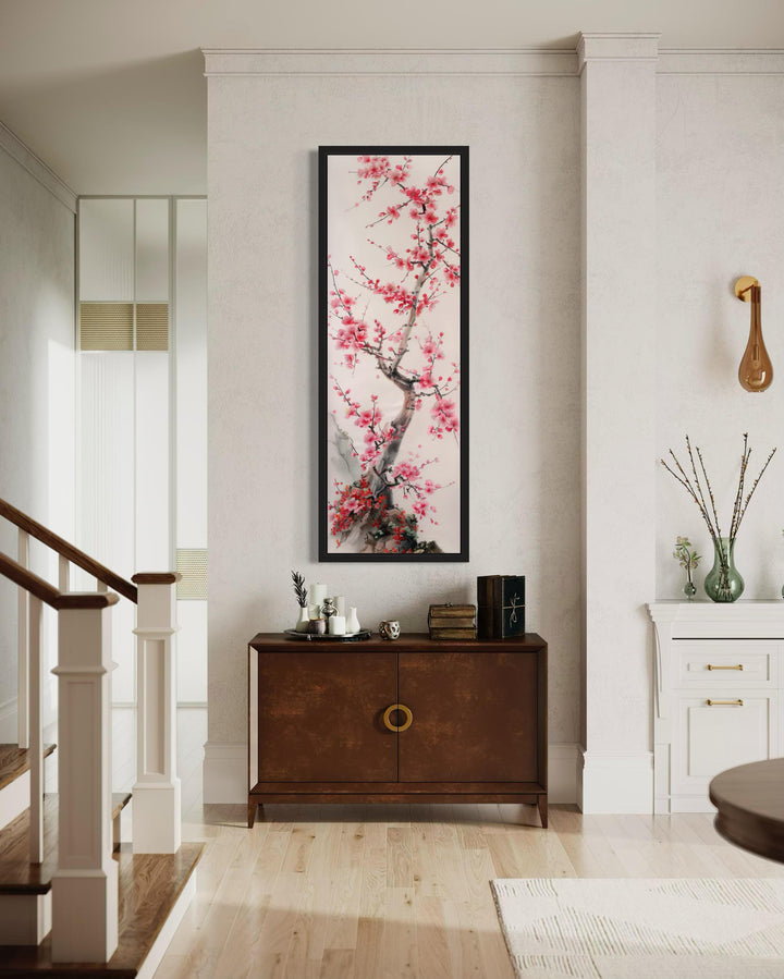 Vertical narrow wall art featuring a cherry blossom tree in a black frame above a wooden cabinet.