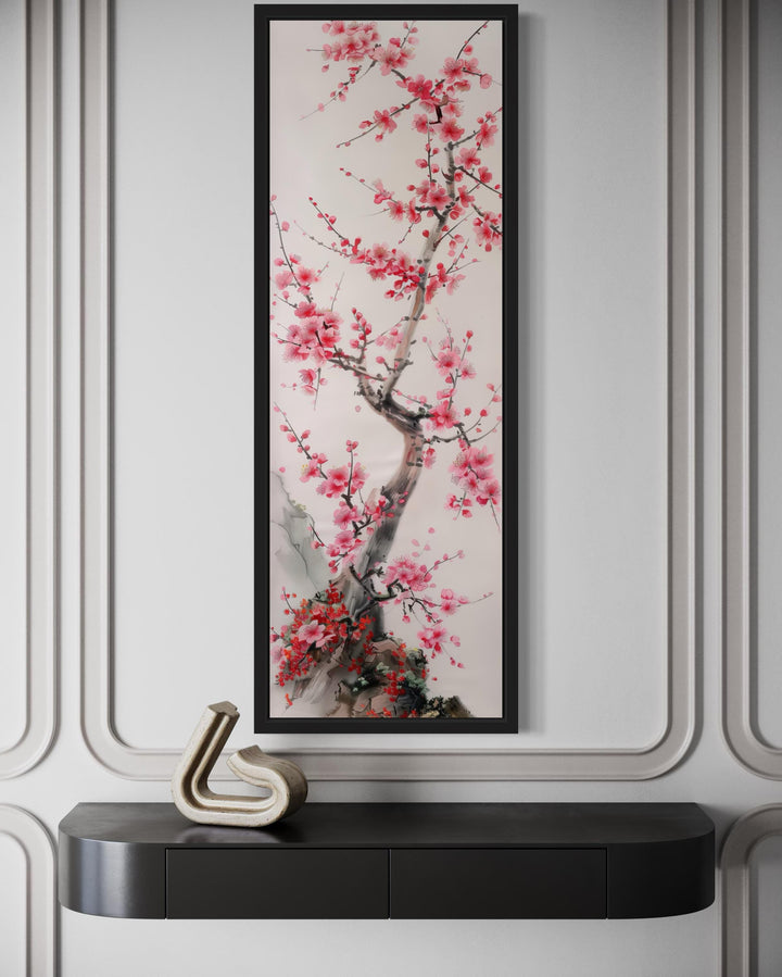 Vertical narrow wall art featuring a cherry blossom tree in a black frame above a dark console.