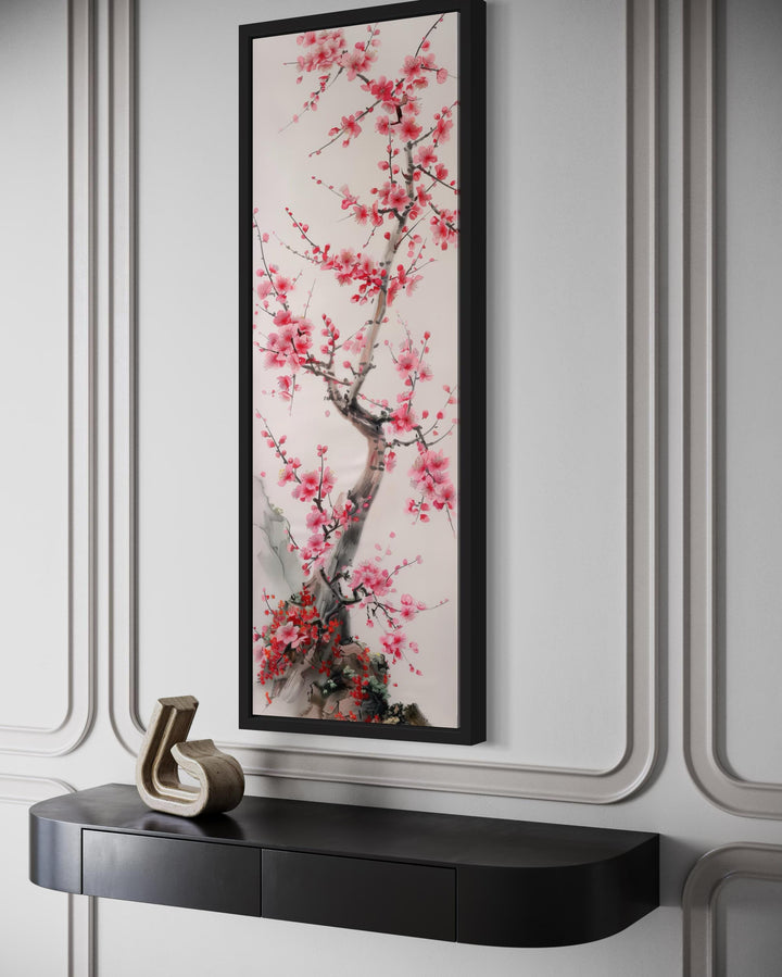 Vertical narrow wall art featuring a cherry blossom tree in a black frame above a console table.