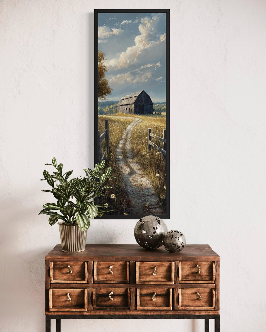 Vertical narrow canvas wall art of a rustic barn in a golden wheat field above a wooden dresser.