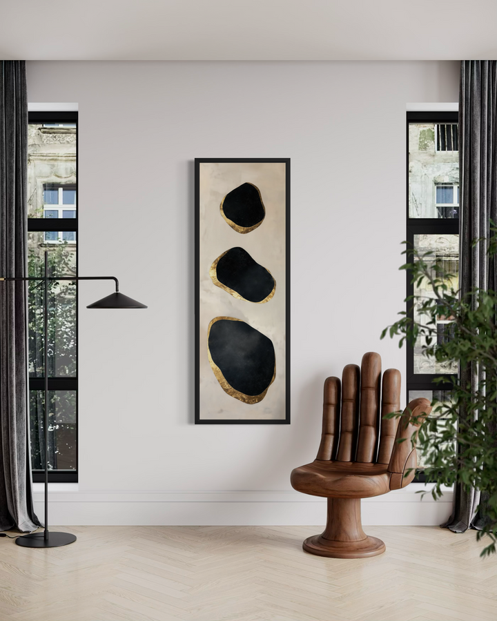 Vertical tall narrow black and gold abstract rocks wall art in a modern room with a hand-shaped chair