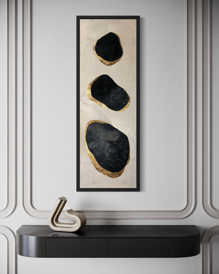 Vertical tall narrow wall art featuring three black and gold abstract rock shapes in a black frame.