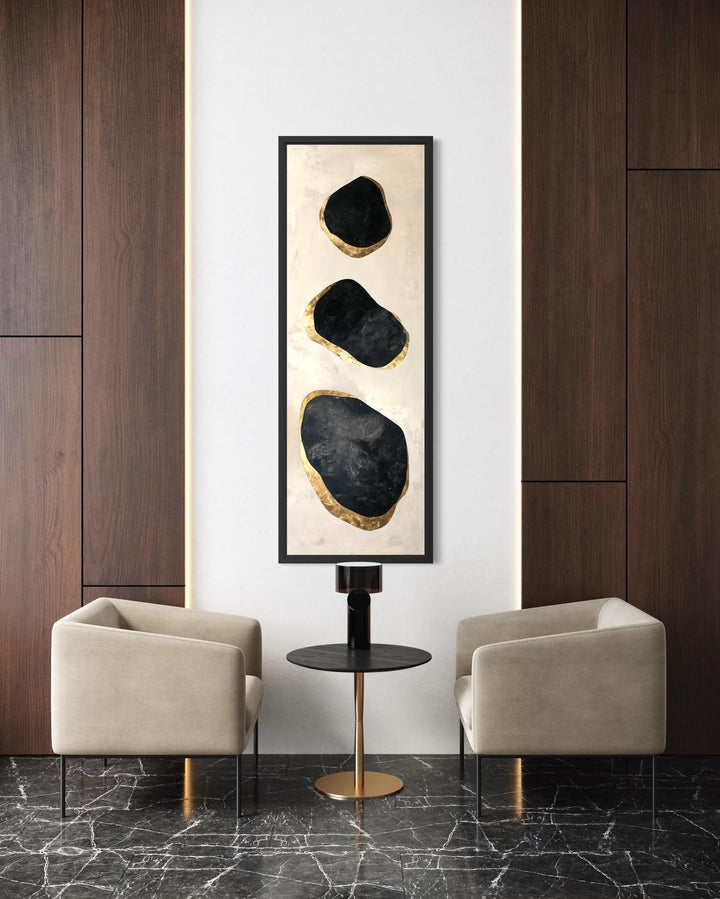 Vertical tall narrow wall art featuring three abstract black and gold rock shapes on a cream canvas.