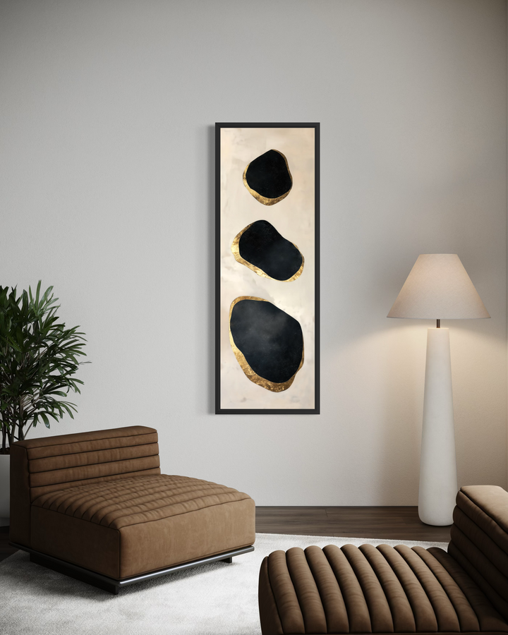 Vertical tall narrow wall art with three black and gold abstract rock shapes on a cream background.