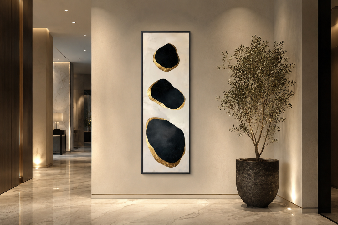 Vertical wall art with three black and gold abstract rock shapes on a neutral textured background.