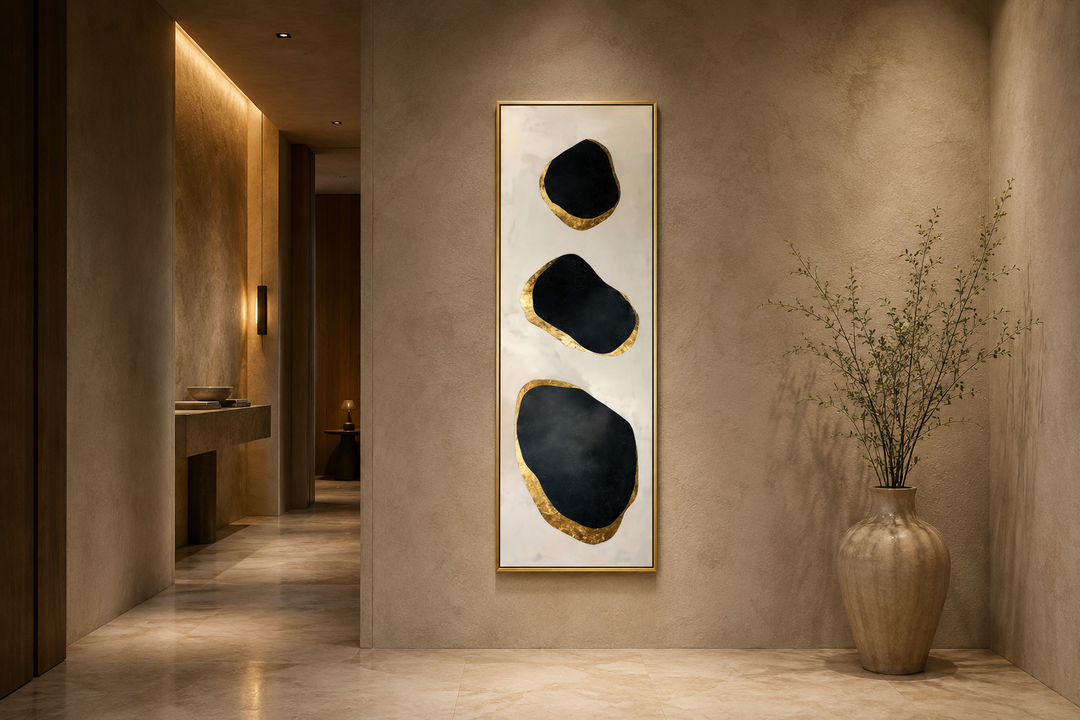 Vertical tall narrow wall art with three black and gold abstract rock shapes on a neutral wall.