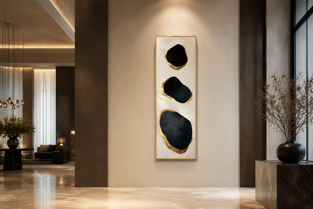 Vertical tall narrow wall art with three abstract black and gold rock shapes in a modern entryway.
