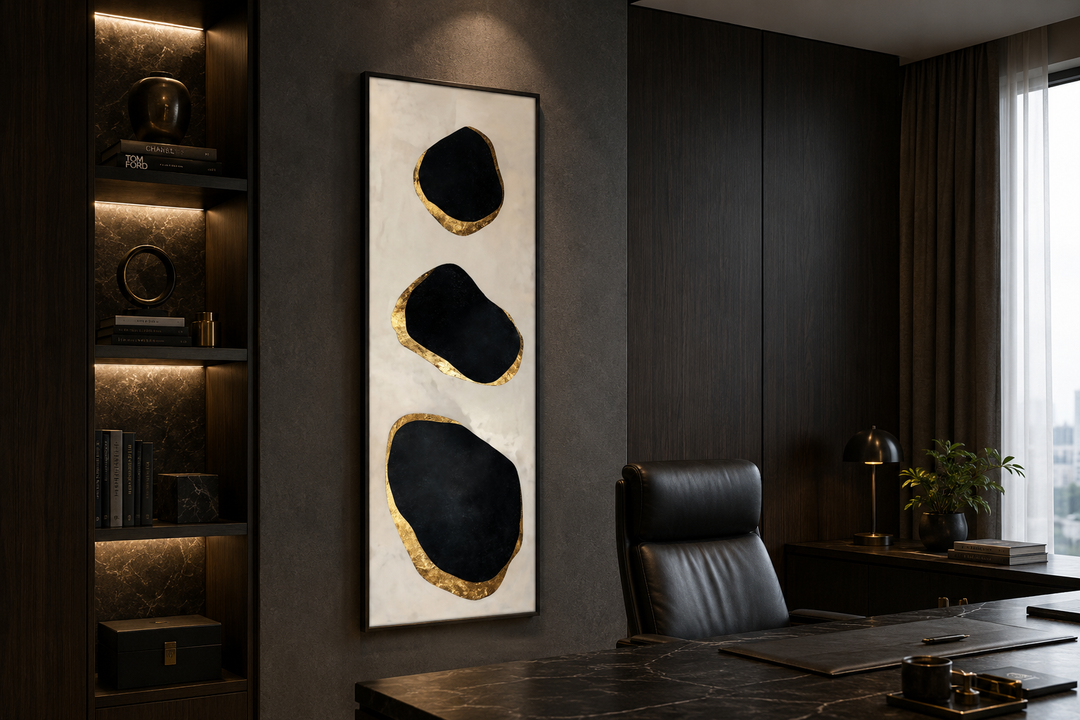 Vertical tall narrow wall art with three black and gold abstract rock shapes in a dark office.
