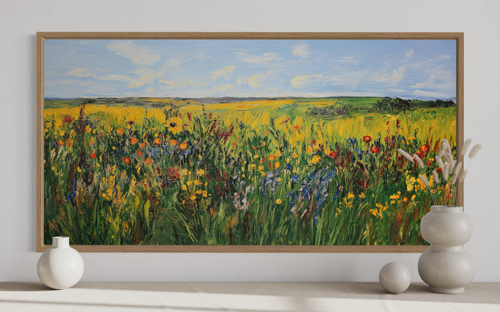 Vibrant impressionist wildflower meadow framed canvas wall art above a console with ceramic vases.