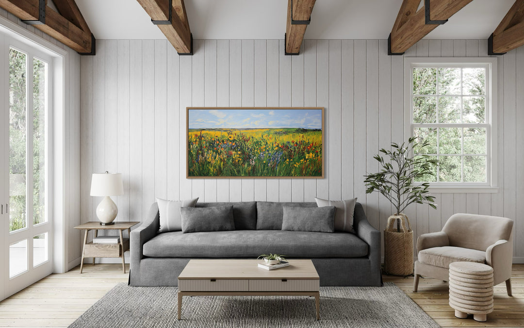 Vibrant impressionist wildflower meadow framed canvas wall art hanging above a gray sofa.