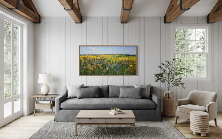 Vibrant impressionist wildflower meadow framed canvas wall art hanging above a gray sofa.
