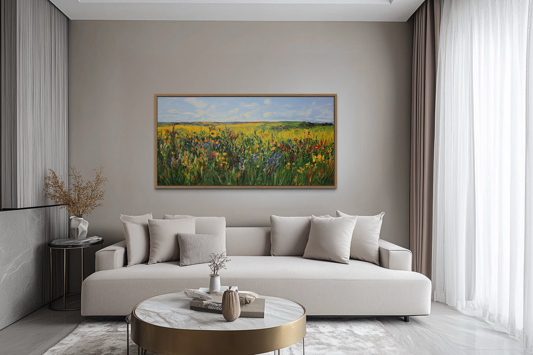 Vibrant impressionist green and yellow wildflower meadow framed canvas art above a modern sofa.