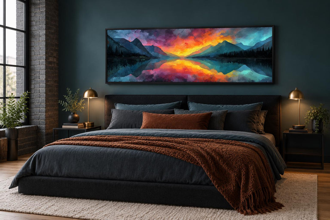 Vibrant mountain lake sunset long horizontal framed canvas wall art above a bed in a dark bedroom.