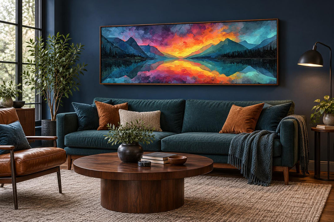 Vibrant mountain lake sunset panoramic framed canvas art above a dark teal sofa in a living room.