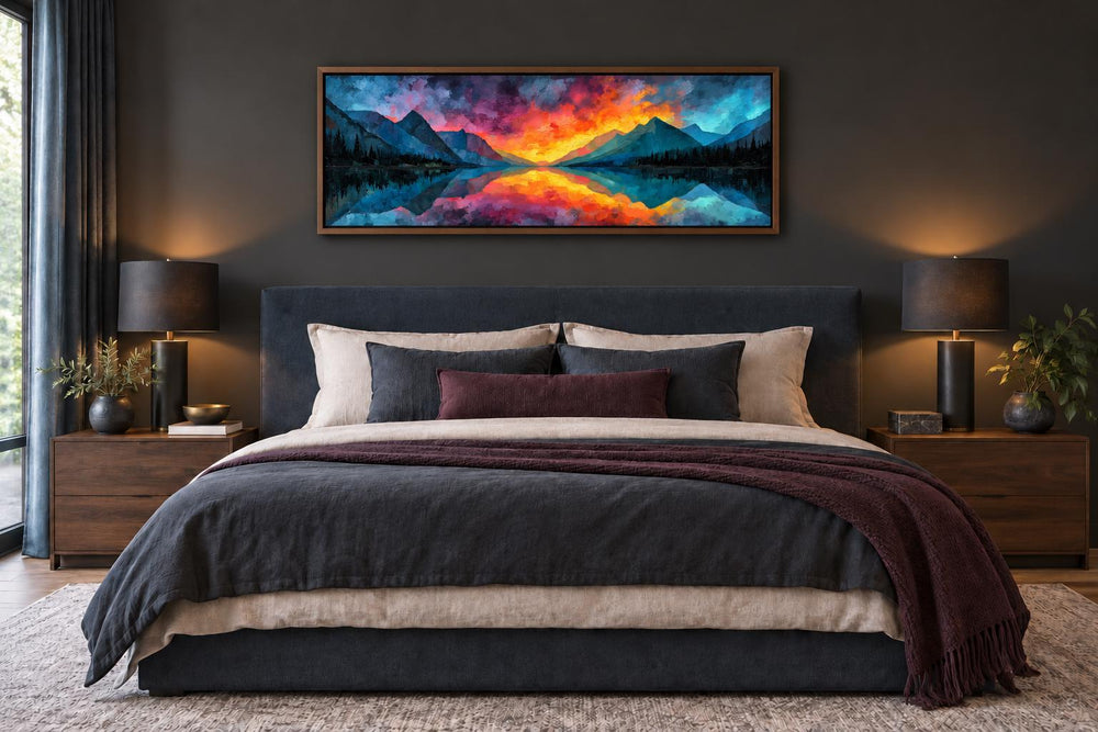 Vibrant mountain lake sunset panoramic framed canvas art above a bed in a dark modern bedroom.