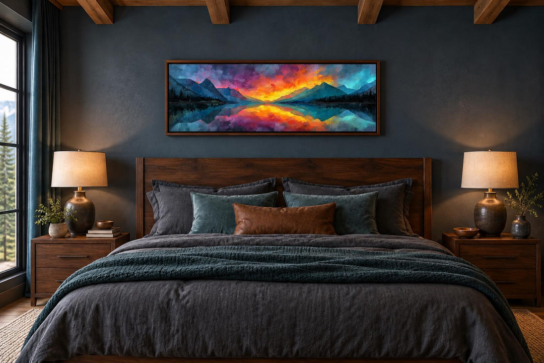 Vibrant mountain lake sunset long horizontal framed canvas wall art above a bed in a dark bedroom.