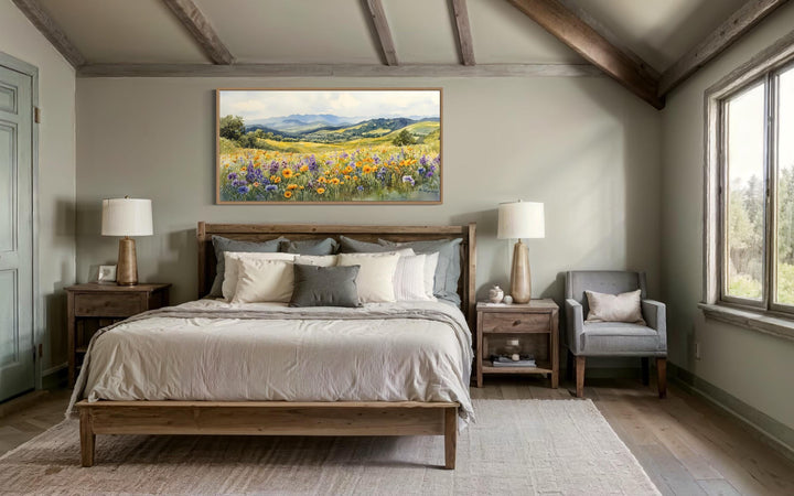 Panoramic canvas wall art of a vibrant yellow wildflower field with mountains above a wooden bed.