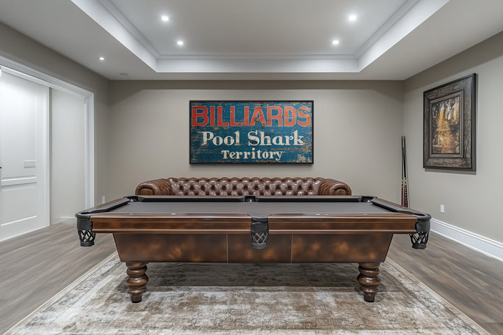 Vintage Billiards Sign with Pool Shark Territory text on a wall above a pool table and leather sofa.