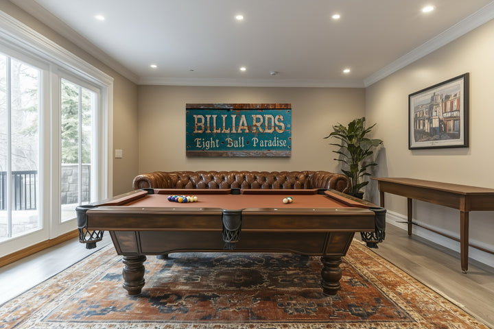 Vintage Billiards Eight Ball Paradise sign on a wall above a pool table and leather sofa.