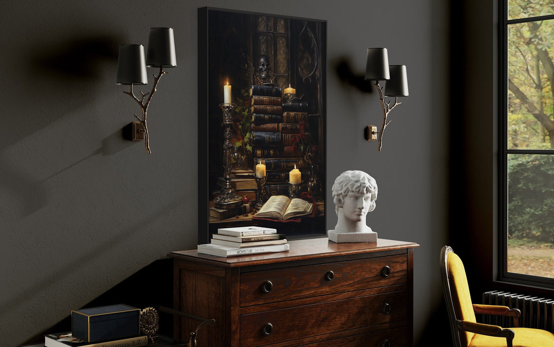 Gothic wall art of vintage books and candles above a wooden dresser in a dark academia room.