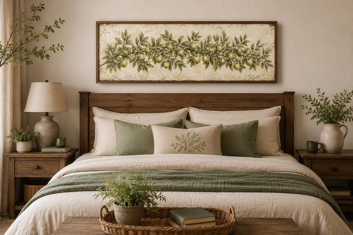 Long narrow vintage botanical canvas painting of a green apple branch above a wooden bed frame.