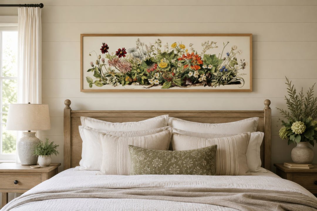 Vintage botanical watercolor wildflower art in a wood frame hanging above a bed.