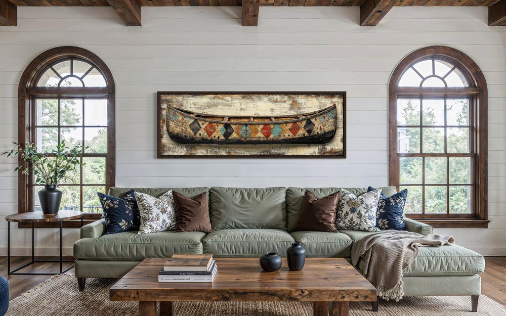 Vintage canoe with Native American patterns on a long horizontal canvas wall art above a sofa.