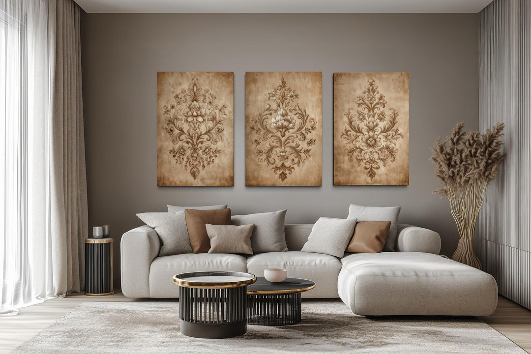 Three vertical canvas prints featuring vintage beige damask patterns above a modern neutral sofa.