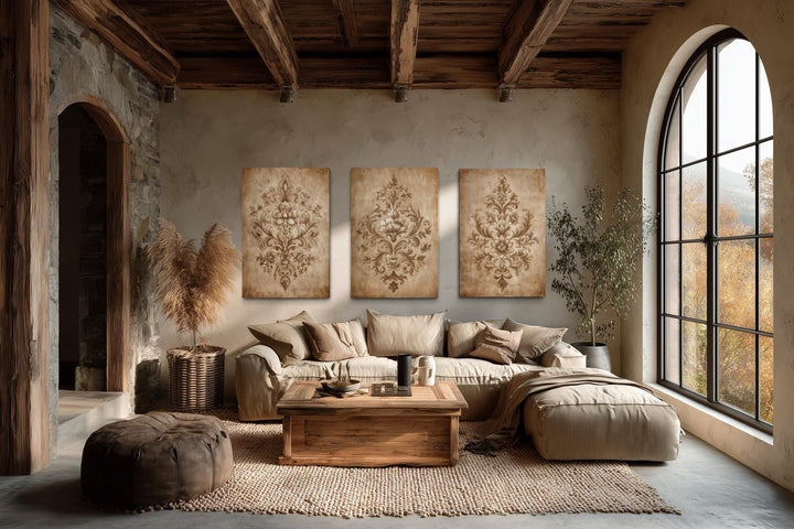 Set of three vintage damask canvas prints with neutral beige ornamental patterns on a living room wall.