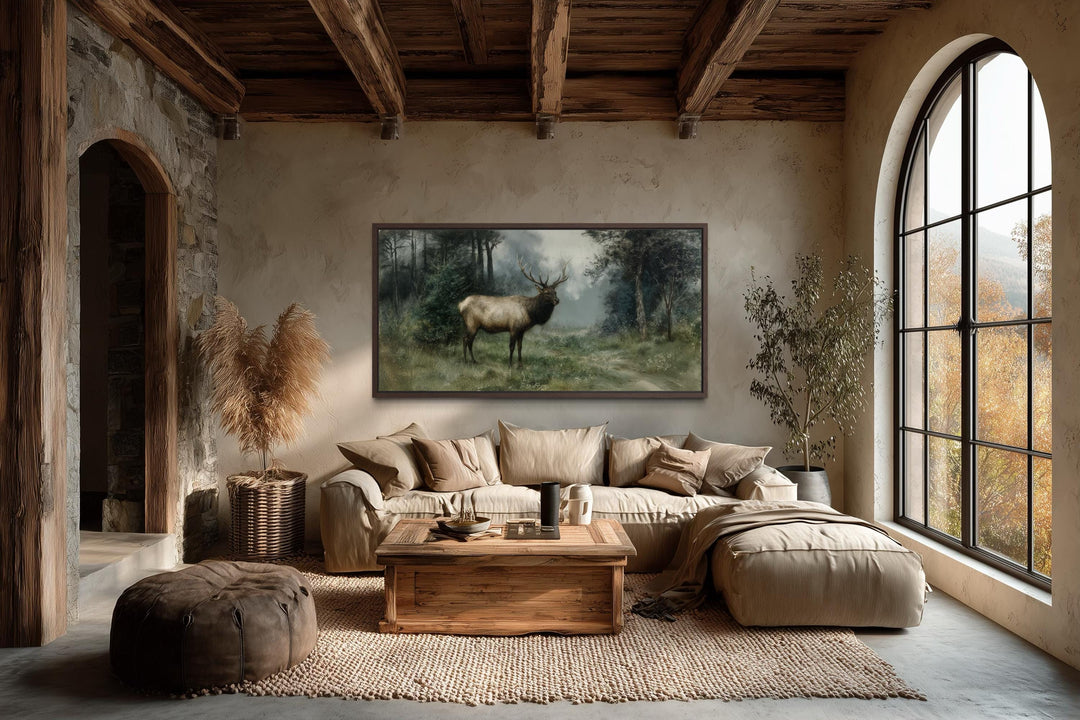 A horizontal canvas print of a majestic elk in a misty forest hangs in a rustic, earthy living room.