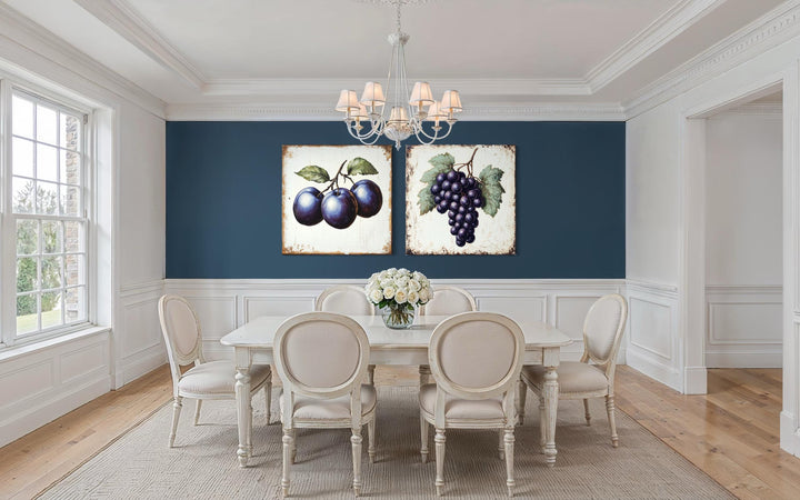 Set of two vintage botanical canvas prints featuring plums and grapes in a classic dining room.